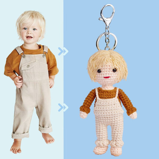 A toddler in a white and brown outfit next to a crochet doll keychain resembling the child, against a blue background.