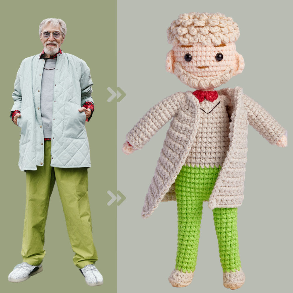 Older man standing next to his crocheted doll look-alike, both wearing similar beige coats, green pants, and white sneakers.