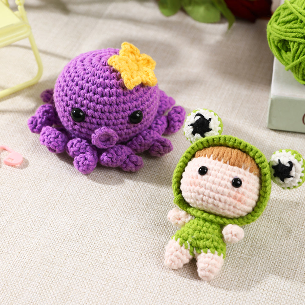 Handmade crocheted toys: a purple octopus with a yellow detail on top and a small human figure in a green outfit with white details, displayed on a textured cloth.