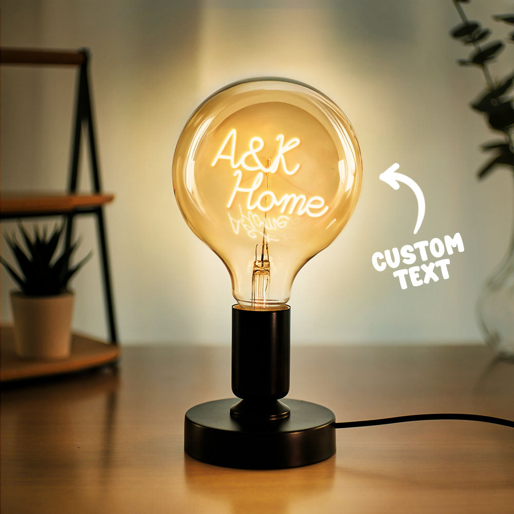 A glowing light bulb on a table with "A&K Home" written inside it, surrounded by plants, with "CUSTOM TEXT" written to the side indicating personalization options.